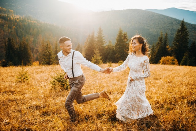 Sunset illuminates mountain hill where wedding couple walks